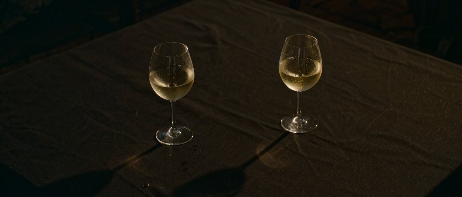 two wine glasses standing apart on a dark table, each in its own small circle of moisture