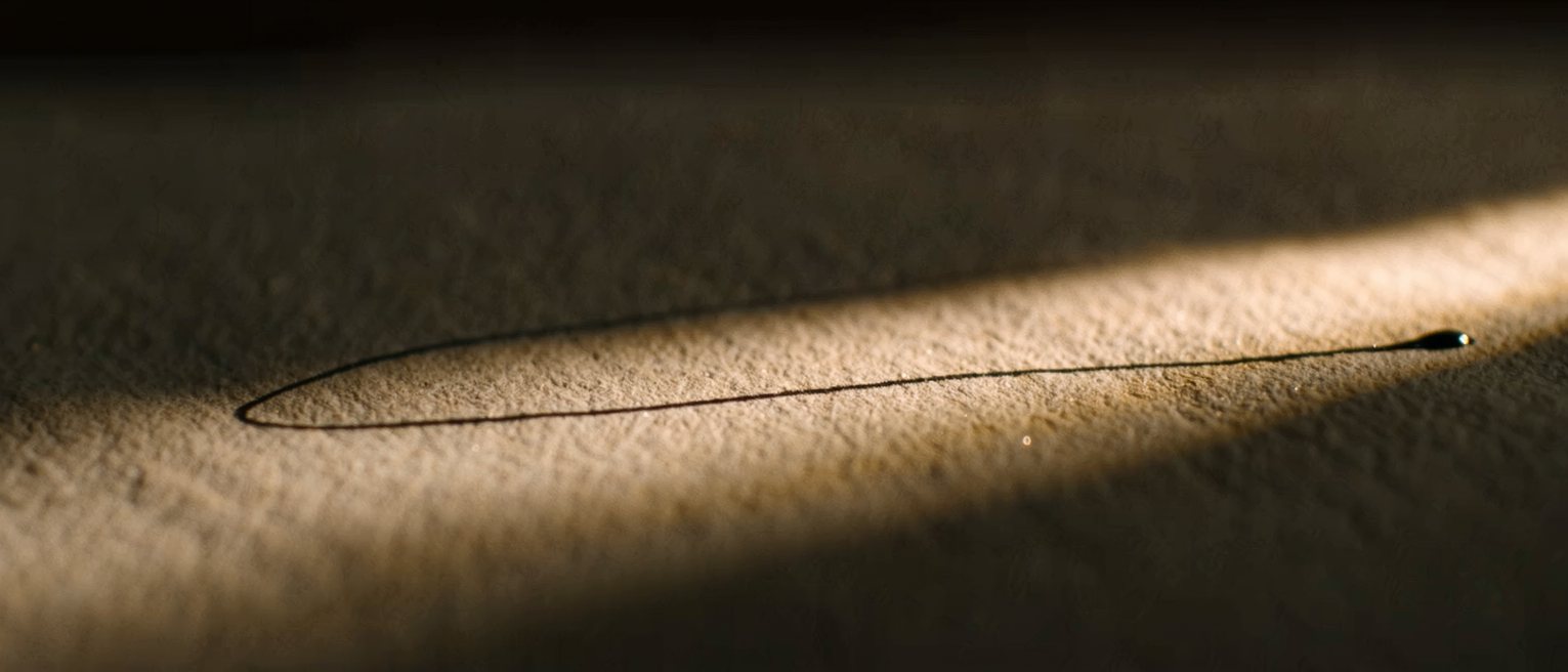 a signature in dark ink on cream paper, the line still wet at its end