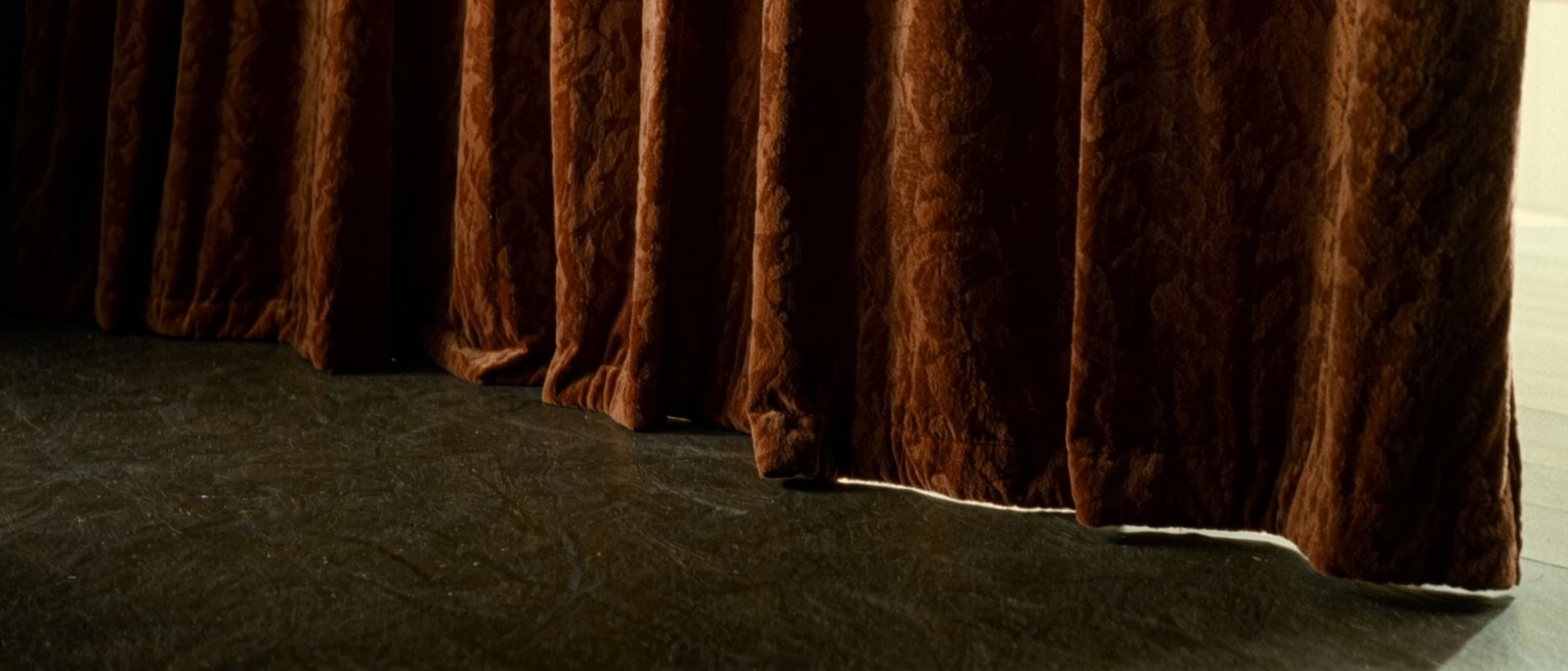 a stage curtain of heavy velvet, drawn closed and lit from its own side