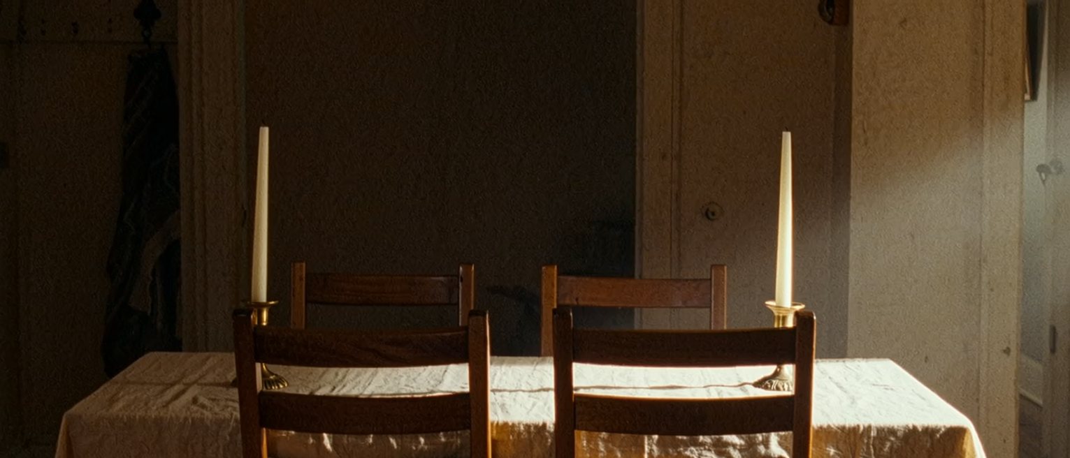 a dining table laid exactly as it is laid every year, the same cloth, the same two candles, the same two chairs