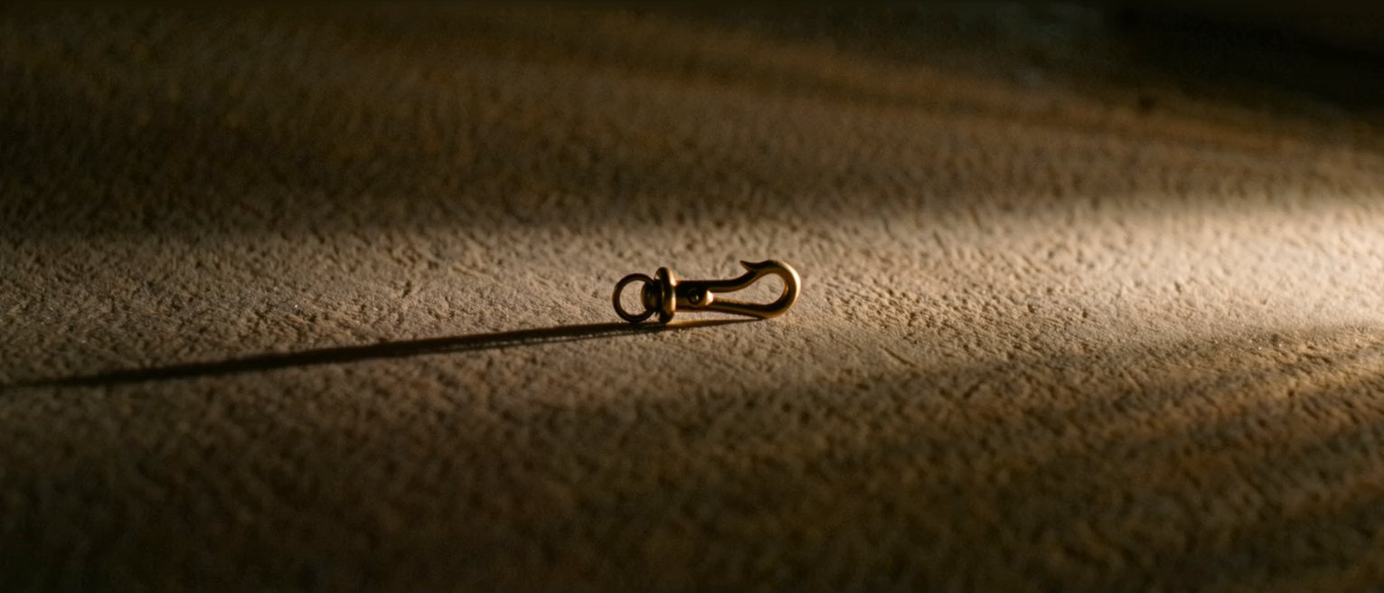 a brass hook holding nothing, the catch left open and free to swing