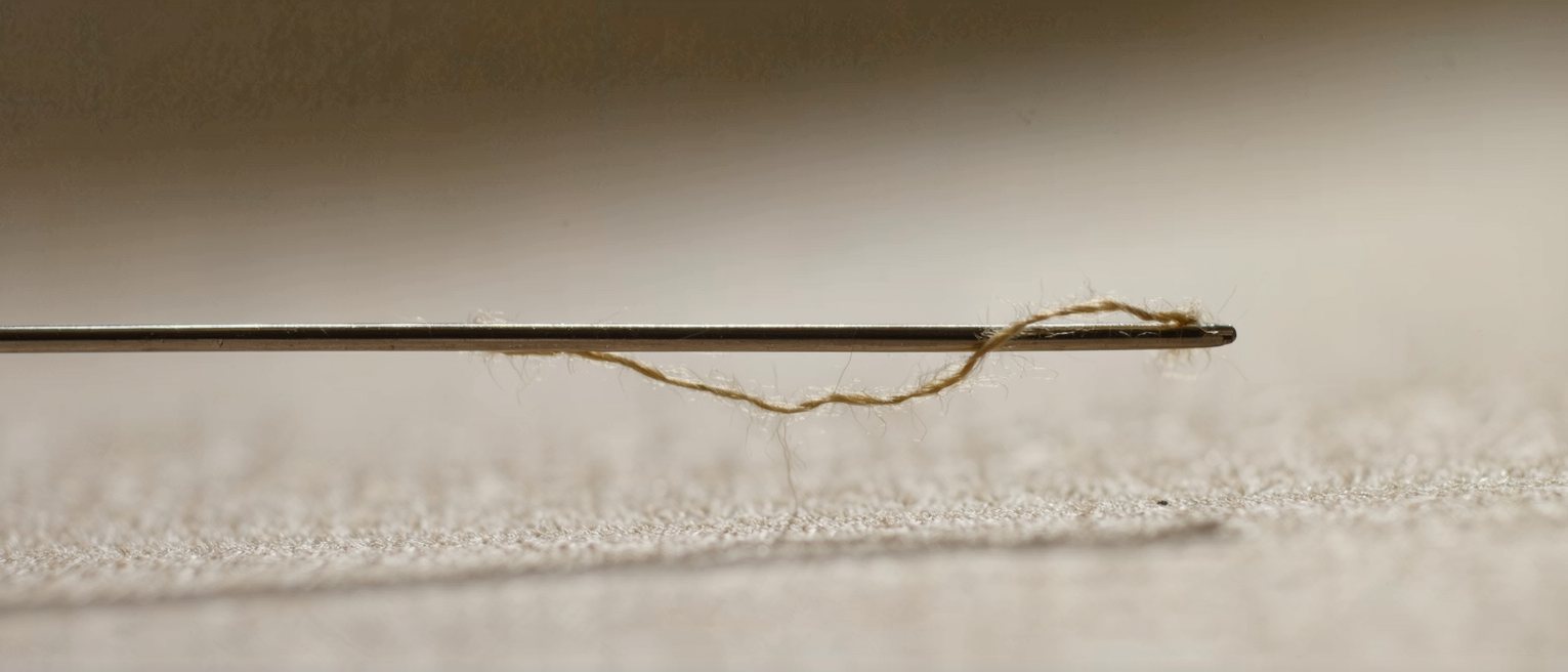 a length of thread under tension between two pins, slack at one end