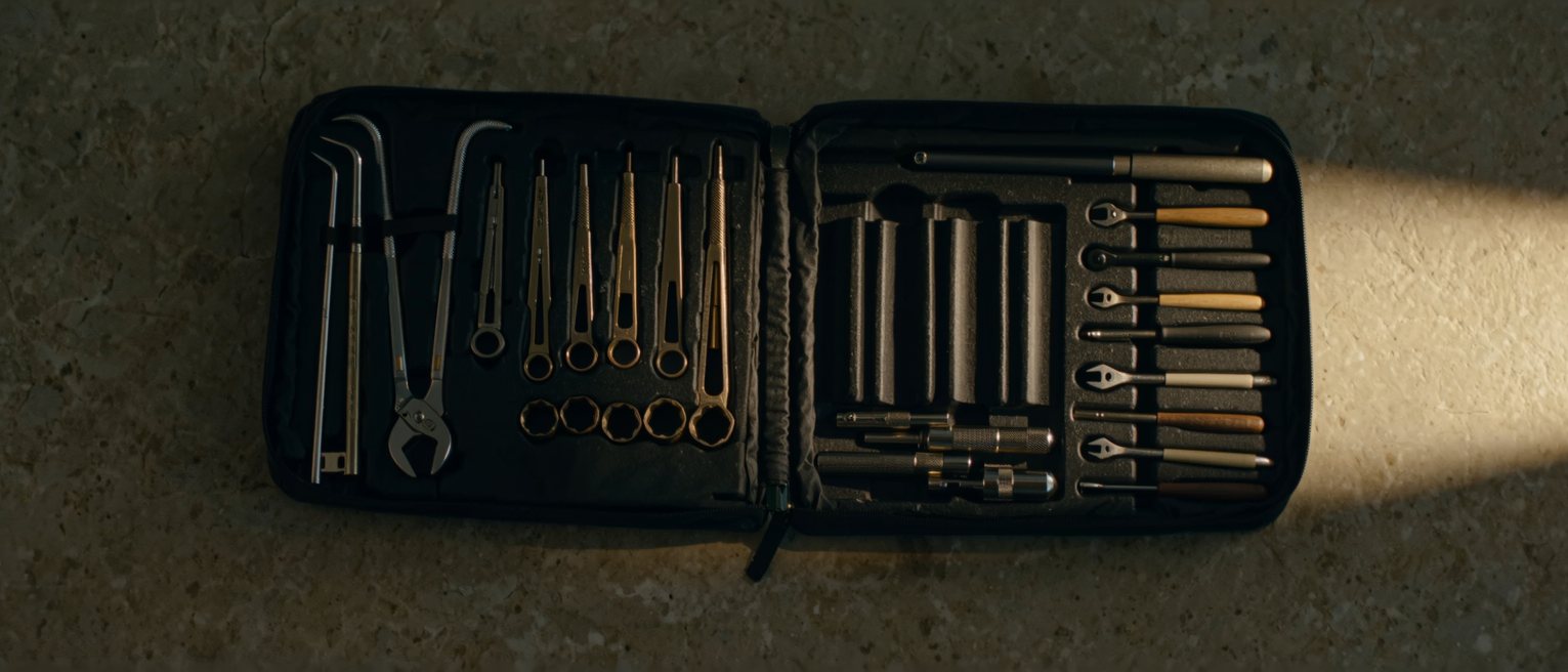 a set of clean tools laid back into their fitted case on a workbench, each one seated in its own recess