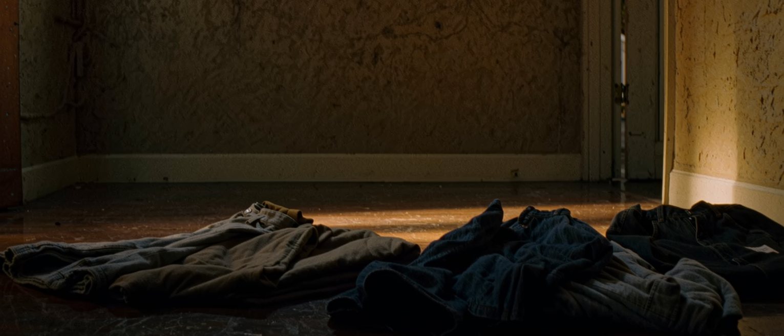 a bedroom with two sets of clothes on the floor and nothing arranged, no note, no cup, no tidying