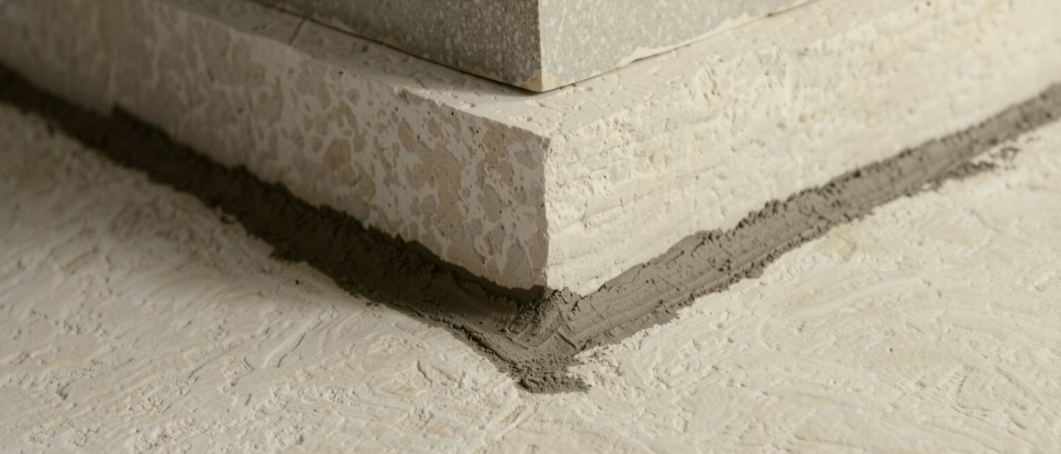 a foundation stone bedded square on fresh mortar at the corner of a wall