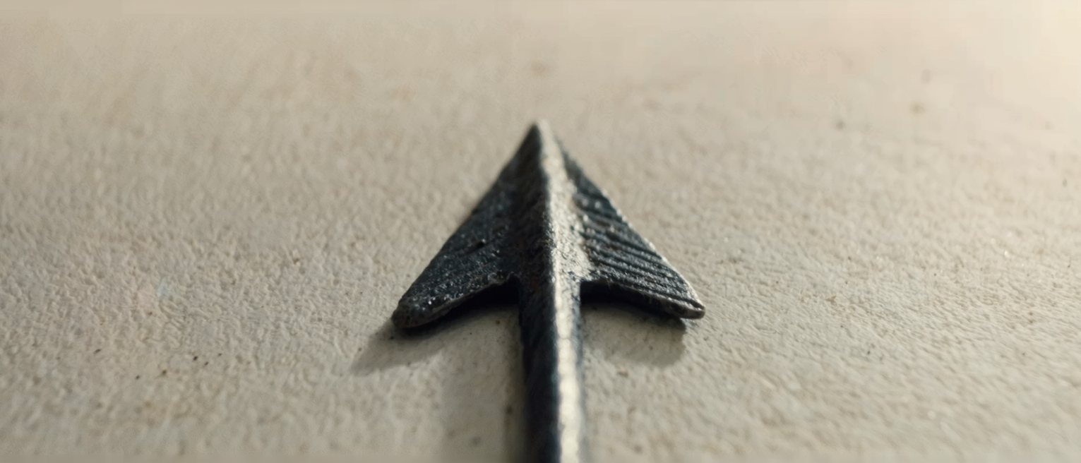 an iron weather vane arrow, its tail fins wide and its pivot clean