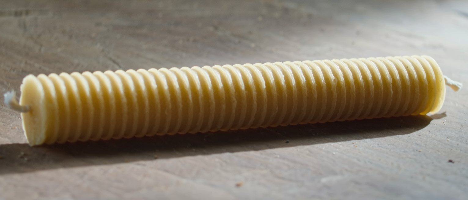 a beeswax candle scored with rings down its whole length, unlit