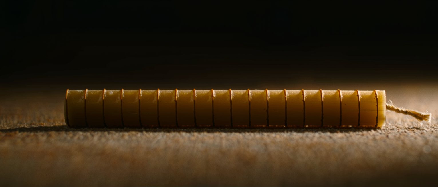 a beeswax candle scored with rings down its whole length, unlit