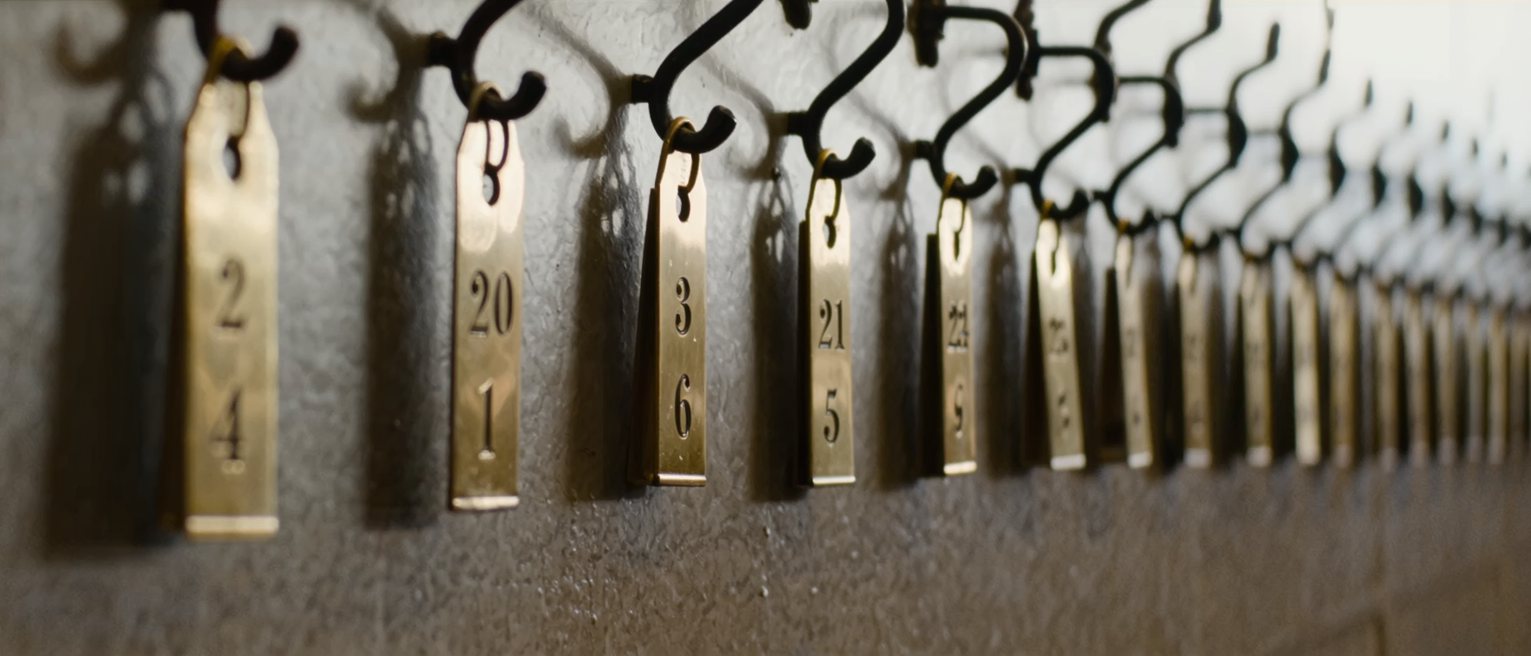 a row of numbered brass cloakroom tags hanging in order on their hooks