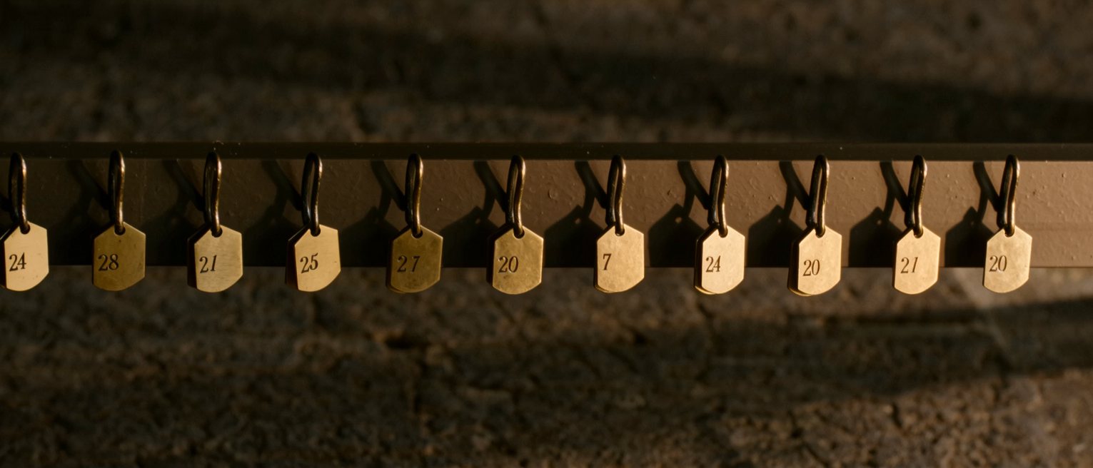a row of numbered brass cloakroom tags hanging in order on their hooks
