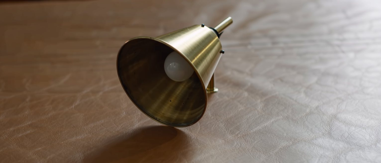 a brass desk lamp with its shade tilted down over a leather desktop