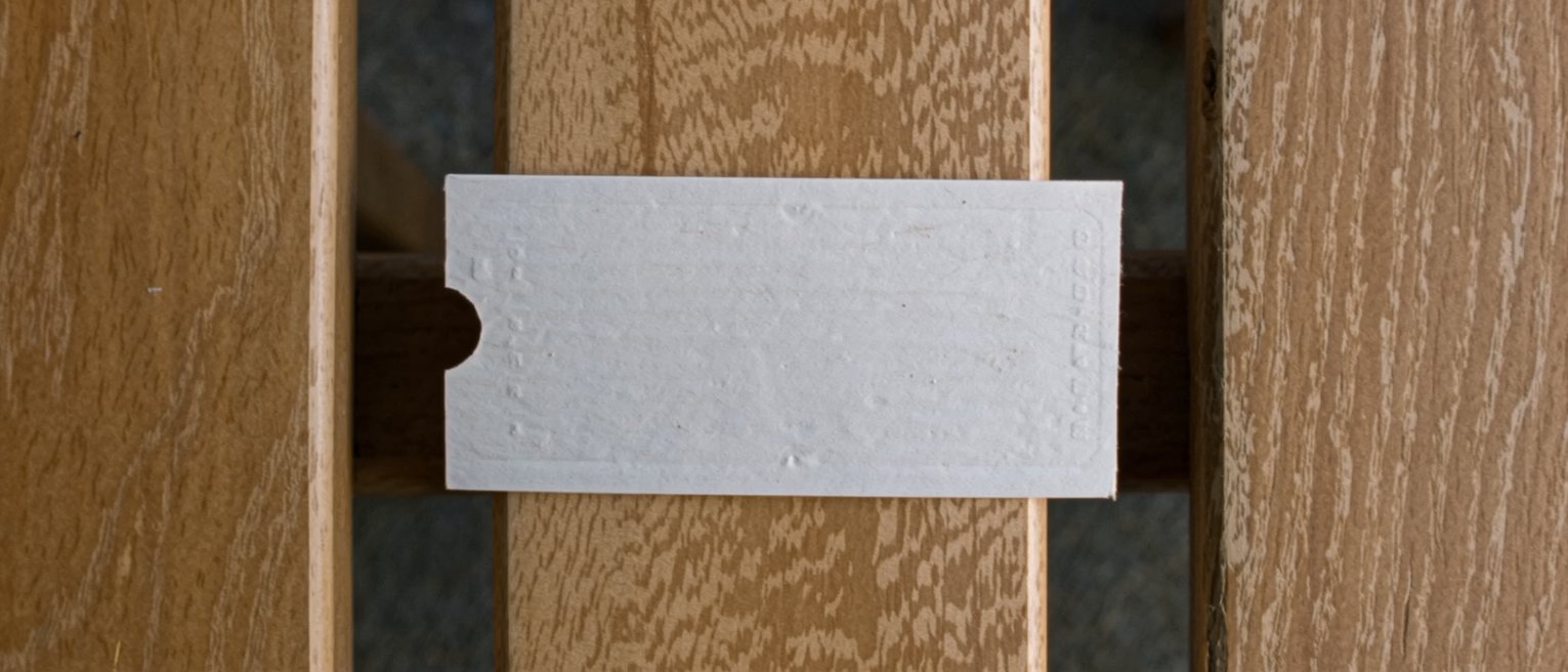 a plain unprinted cardboard ticket punched once, lying on a wooden bench