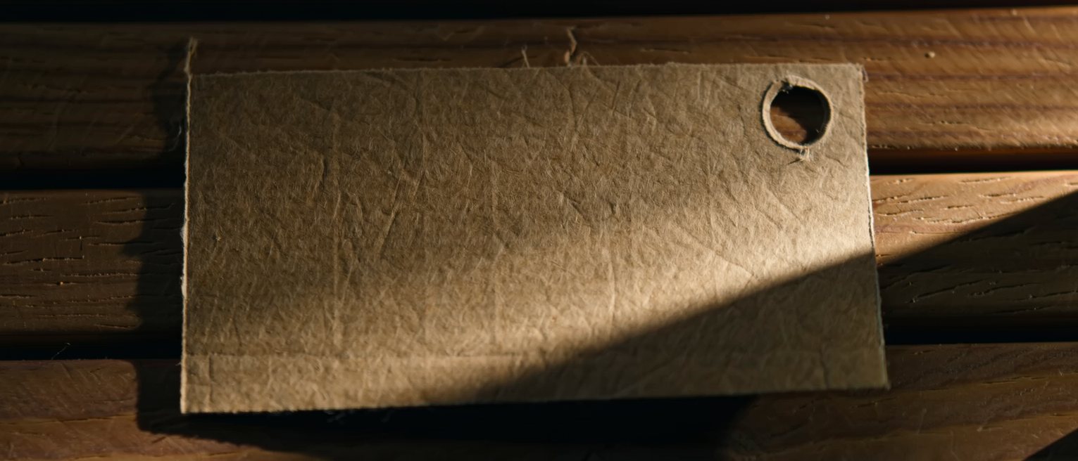 a plain unprinted cardboard ticket punched once, lying on a wooden bench