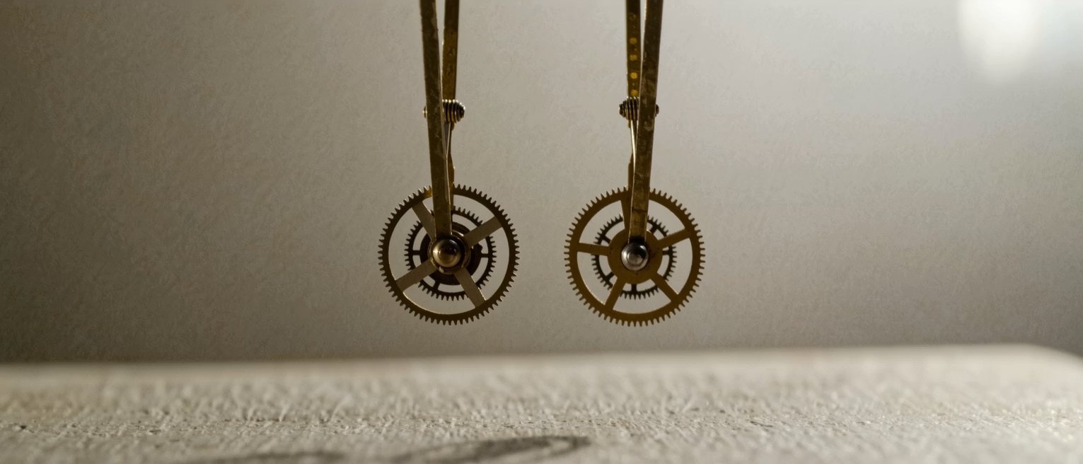 two brass pendulum movements side by side, bare gearwork and bob, their pendulums swinging out of step