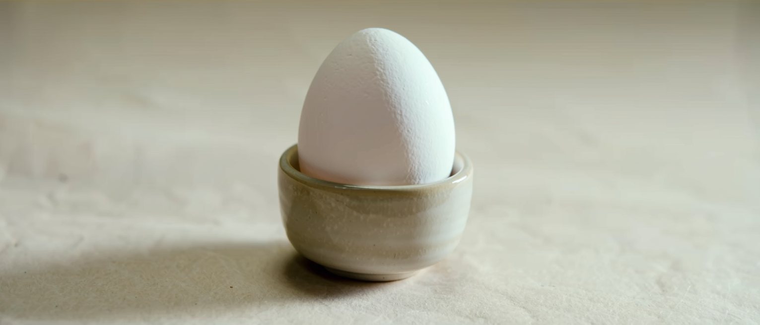 a hen's egg standing in a small ceramic cup