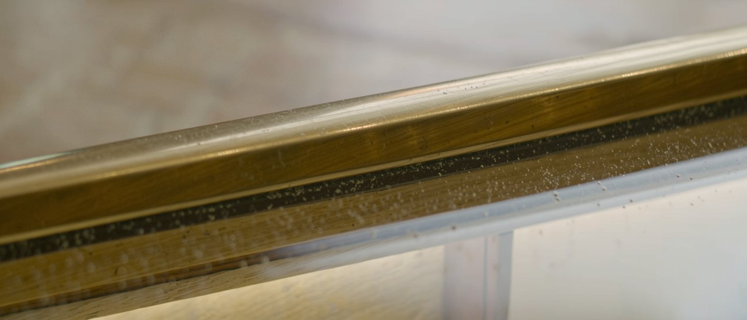 the brass rail and polished glass of a department store display counter