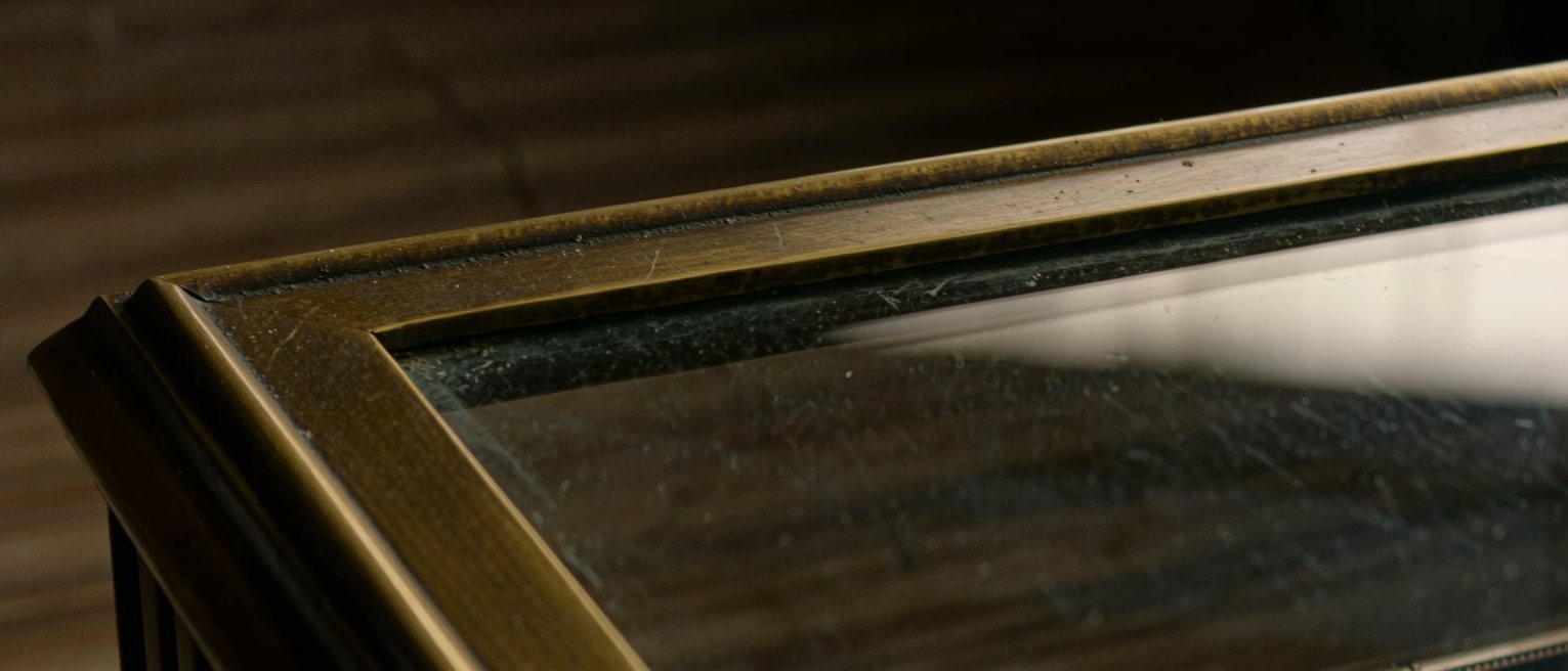 the brass rail and polished glass of a department store display counter