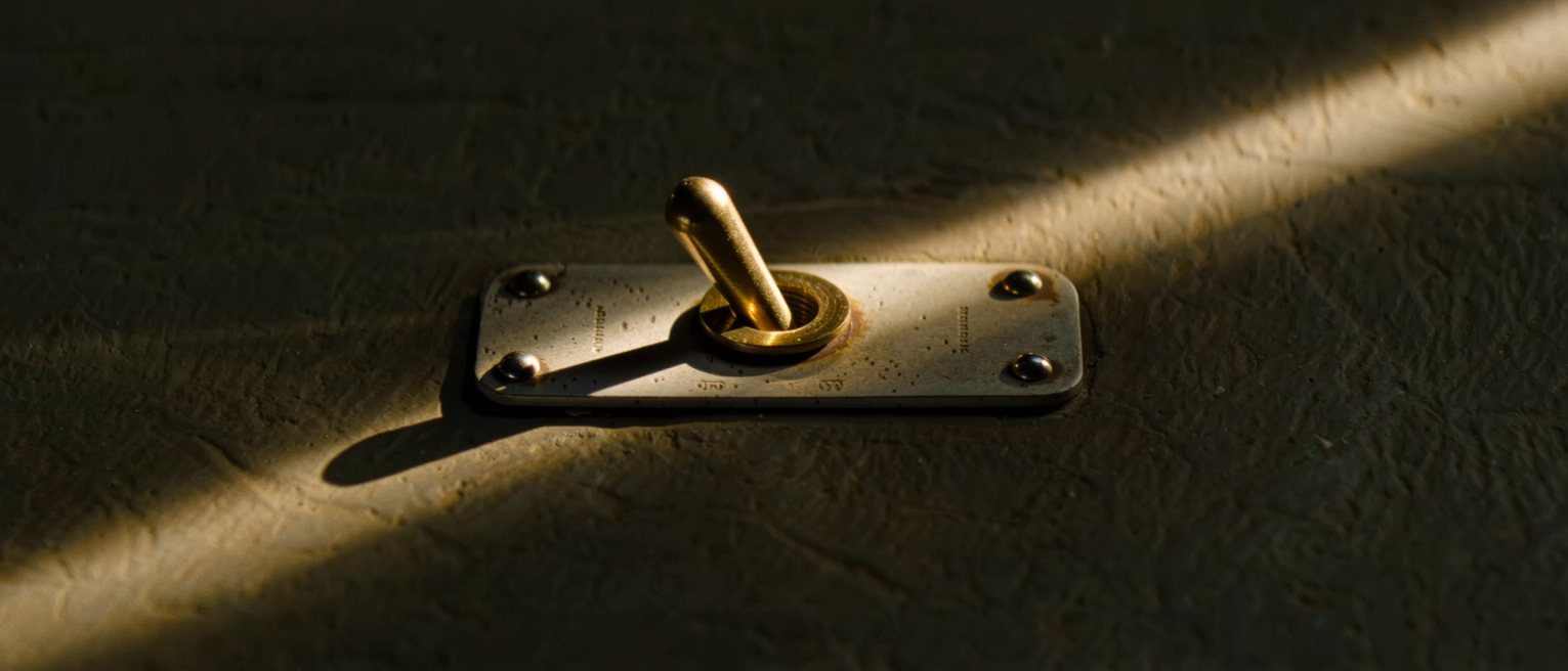 a single brass toggle switch on a mounting plate, thrown hard to one side