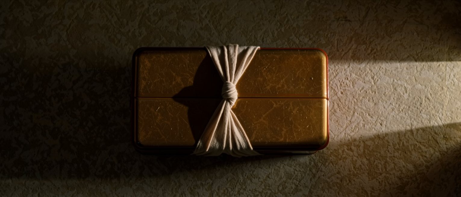 a lacquer lunch box tied up in a plain cloth, the knot squared