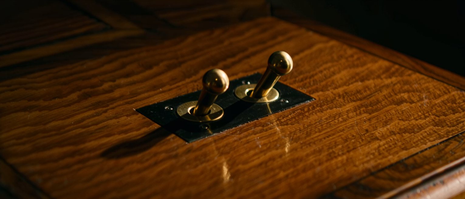 the two brass levers of a throttle quadrant on a varnished timber console, one pushed forward and the other drawn back