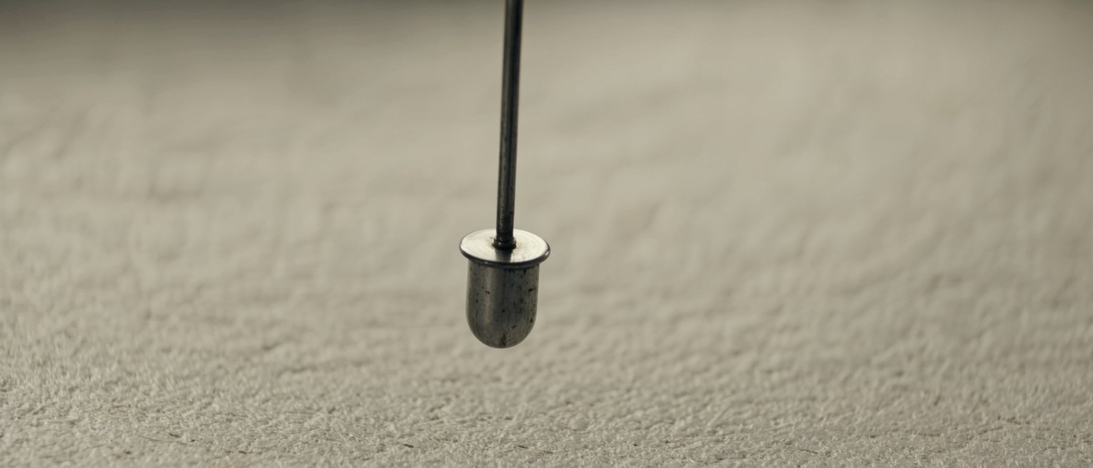 a slow pendulum caught mid-swing, the pivot polished from years of it