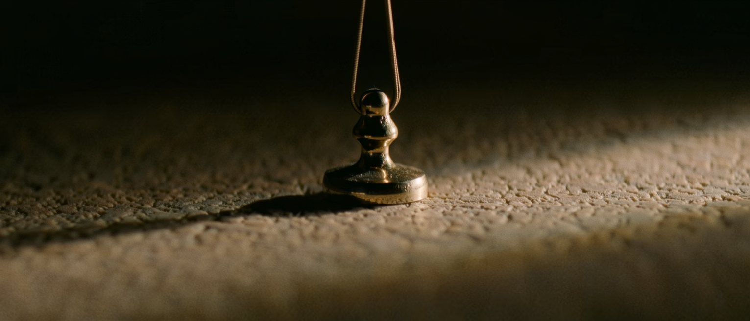 a slow pendulum caught mid-swing, the pivot polished from years of it