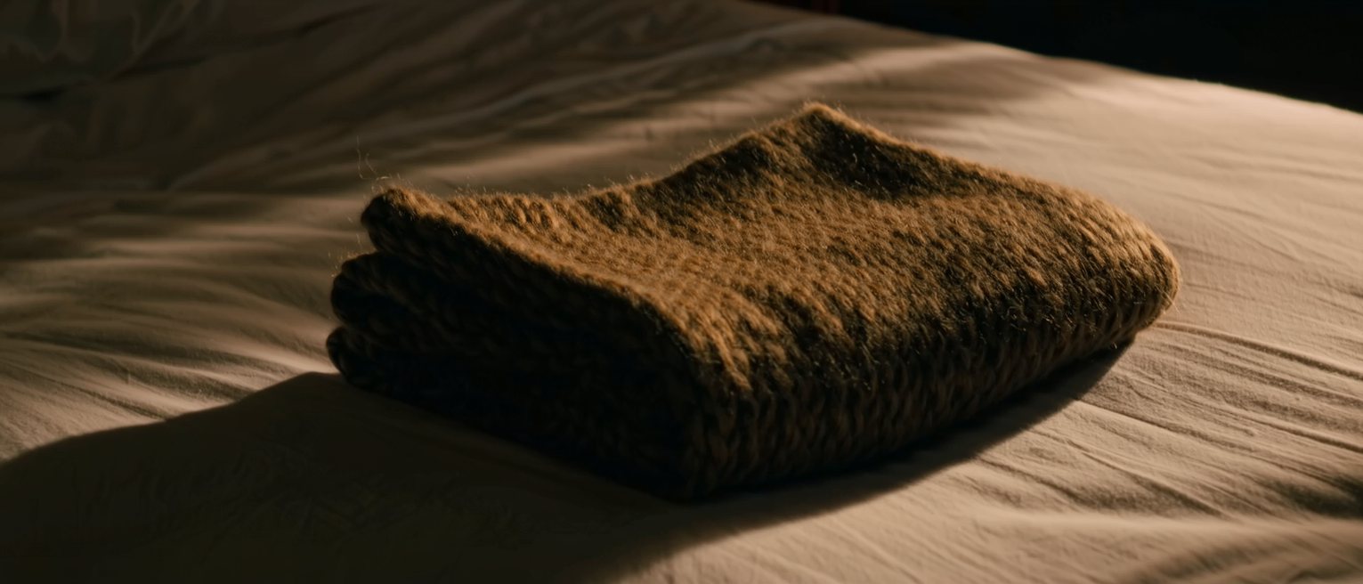 a heavy wool blanket folded once and left at the foot of a made bed