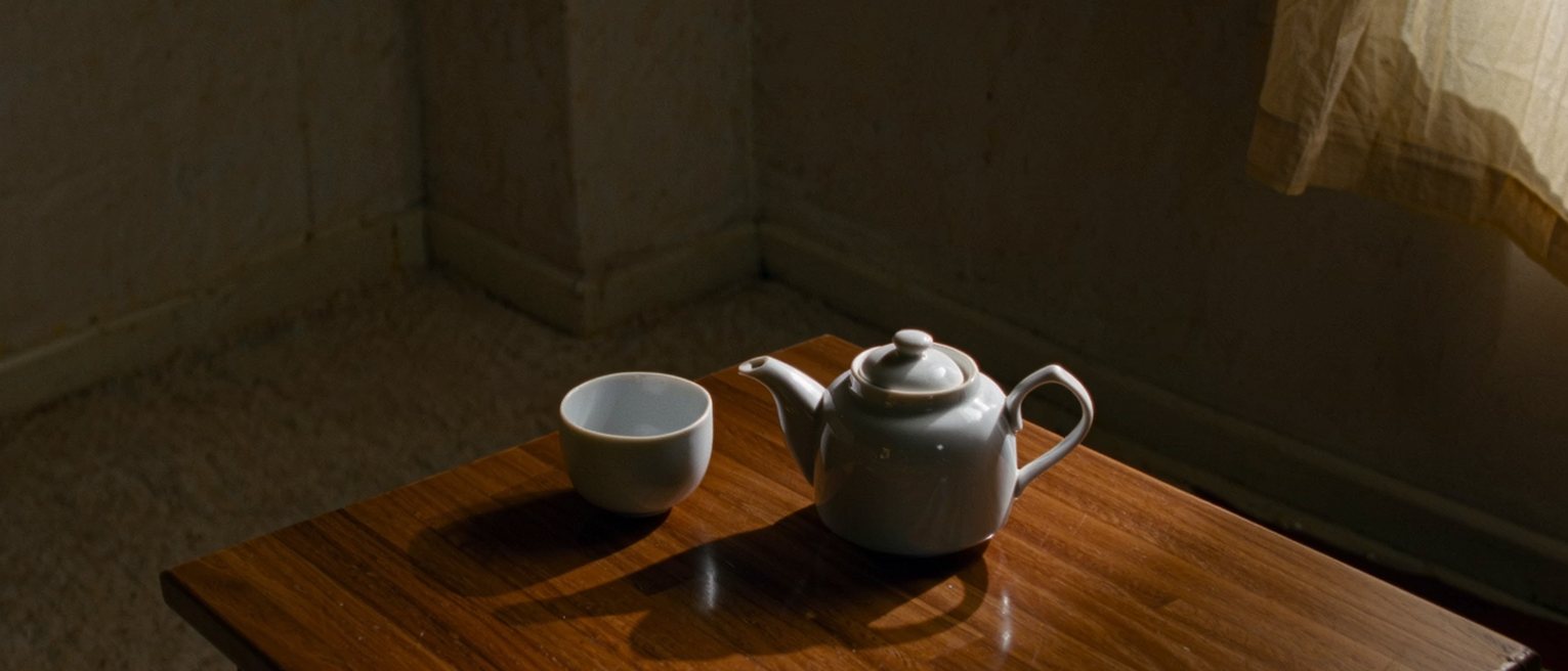 a small table set for two with a pot of tea and nothing else on it at all, no phones, no post, no keys