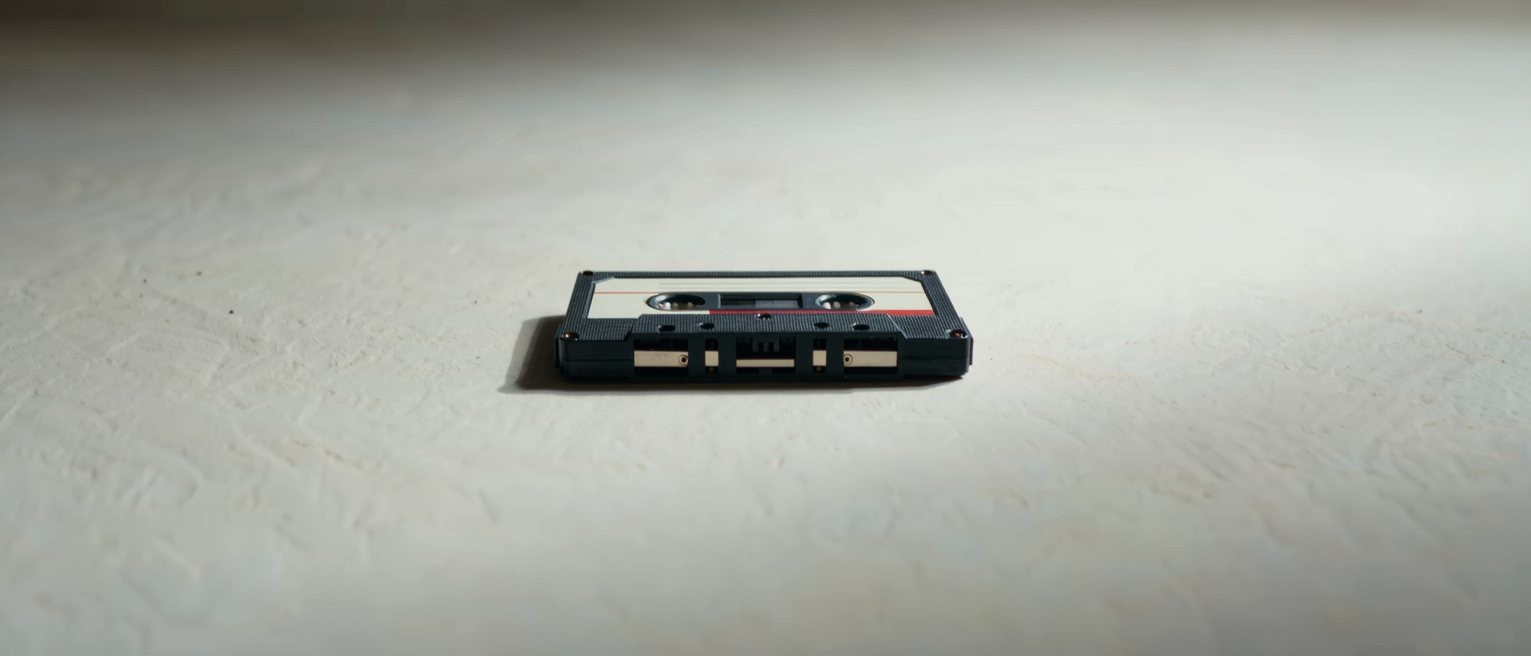 a cassette tape out of its case with a blank unwritten label, the tape wound hard to one side