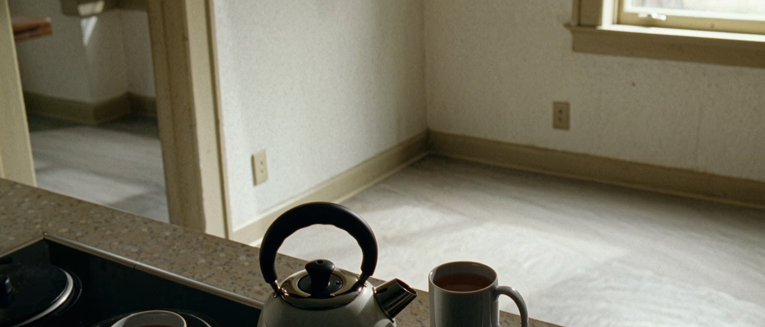 a kitchen where two mugs of tea have been made and one has gone cold untouched beside the kettle