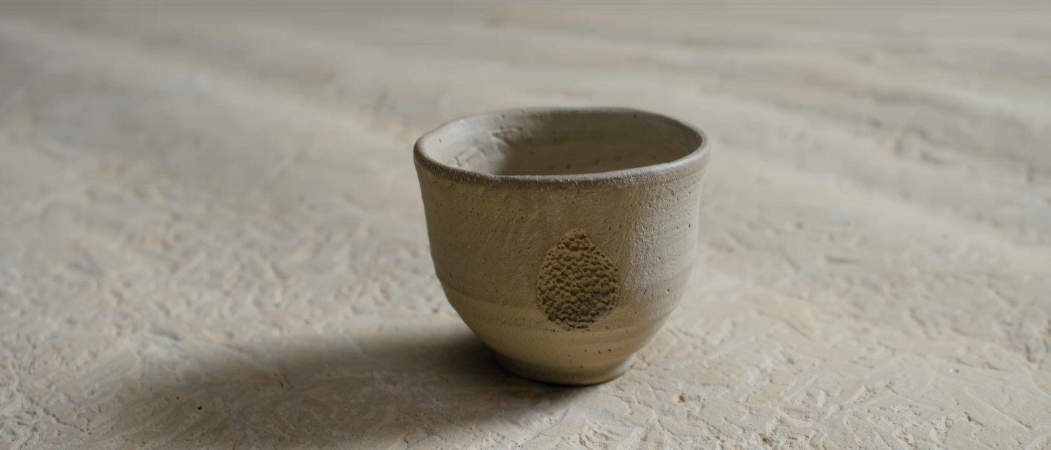 a hand-thrown cup with a thumb-mark left in the clay and fired that way