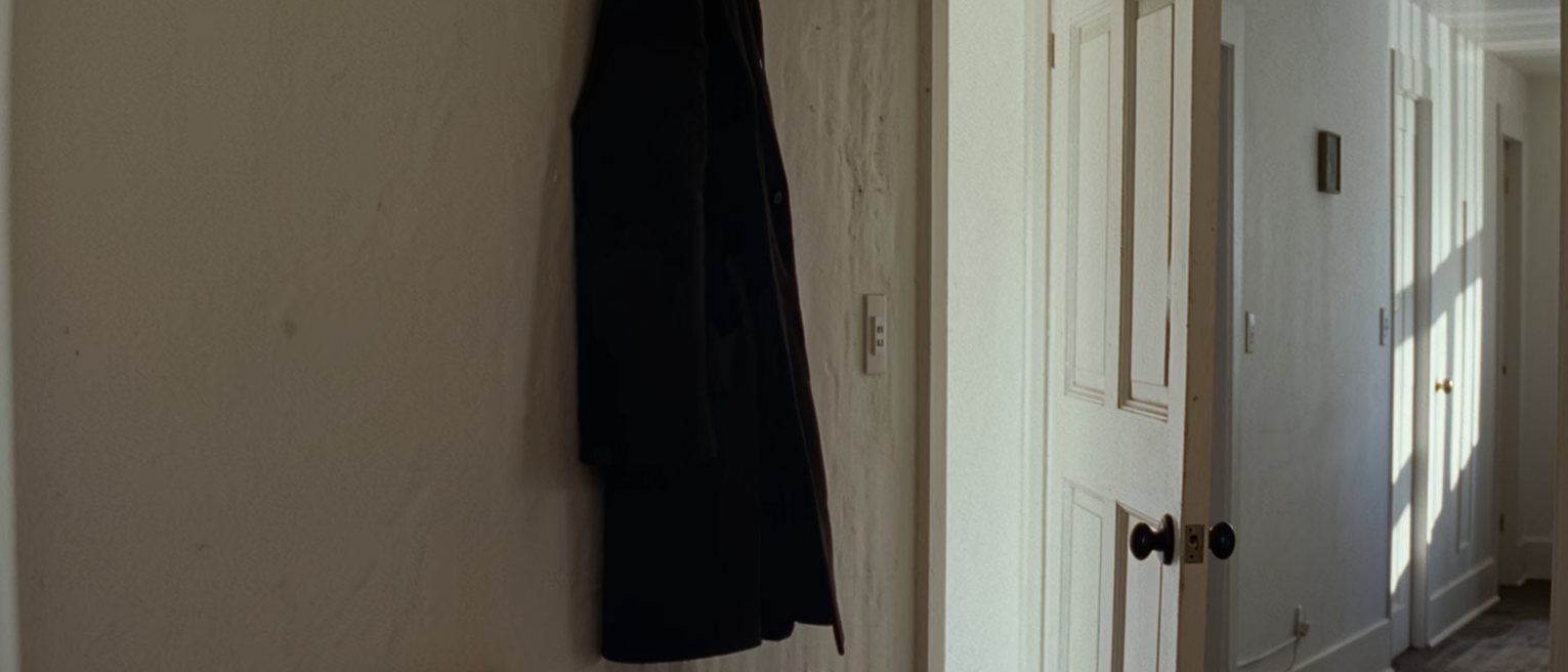 a hall with the front door left on the latch and one coat hung ready, the hall table cleared of everything but a single key