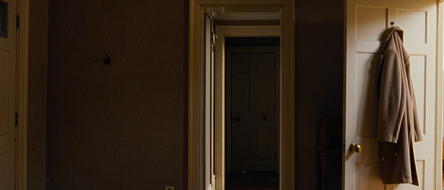 a hall with the front door left on the latch and one coat hung ready, the hall table cleared of everything but a single key