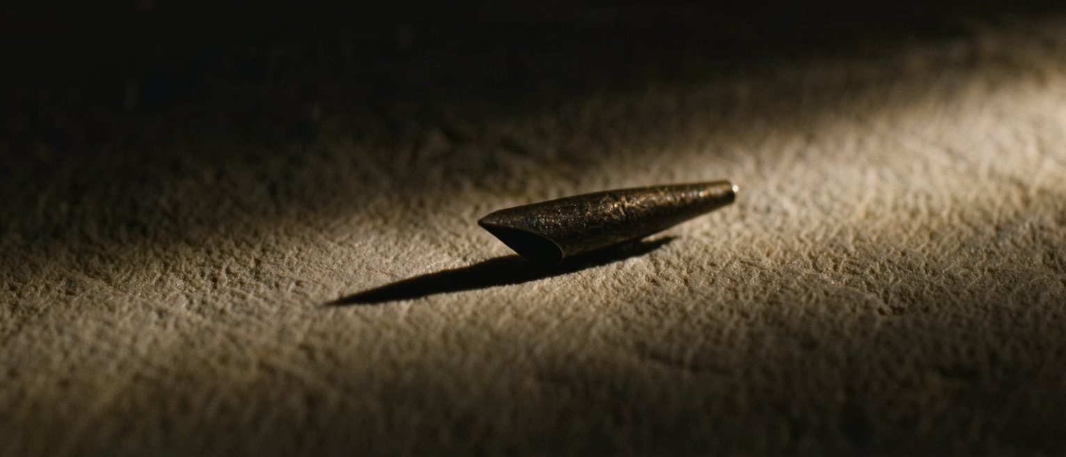 a steel pen nib with a split tip, its shoulders bright