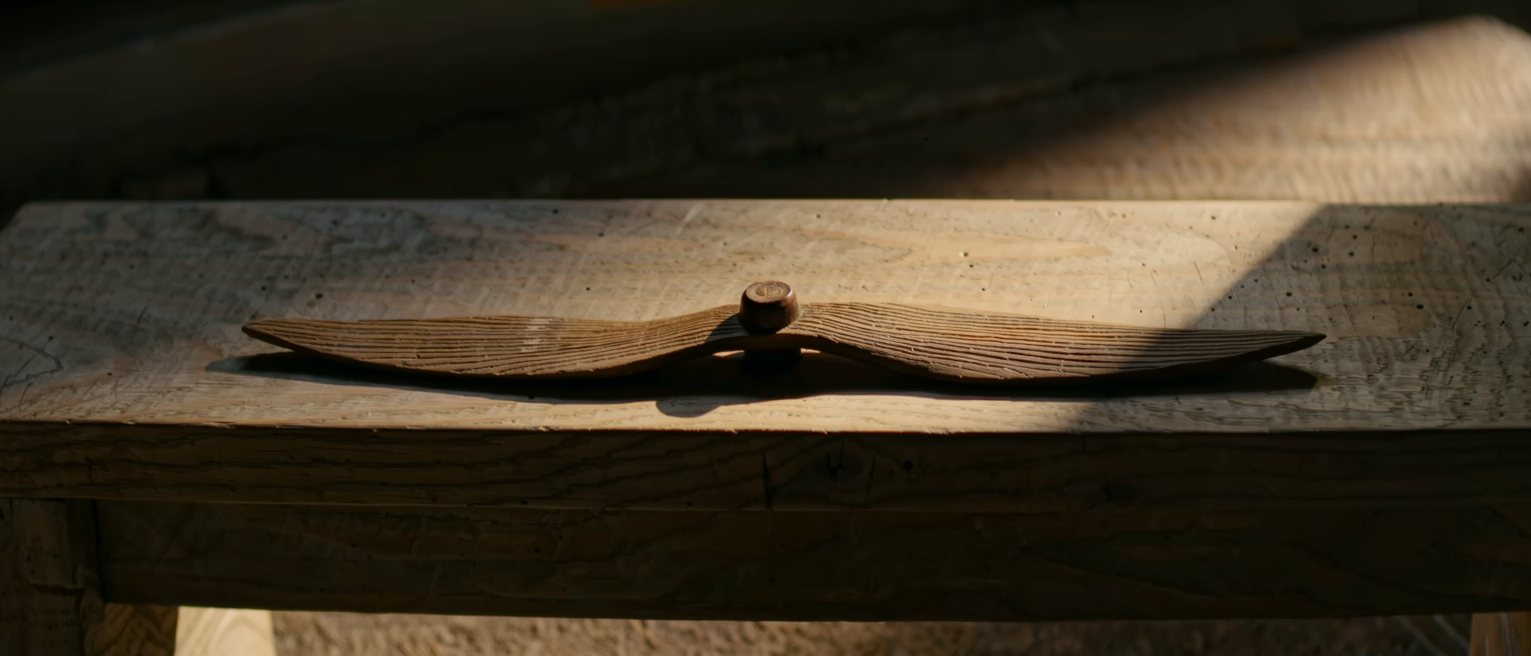 a carved wooden propeller lying on a bench, its blades true