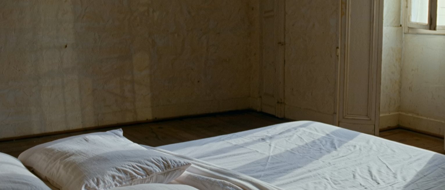 a bedroom where a new set of good linen has been put on the bed and the folds from the packet still show across it