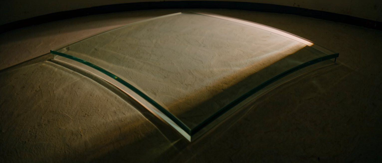 a thick curved wall of clear glass, the light bending as it passes through