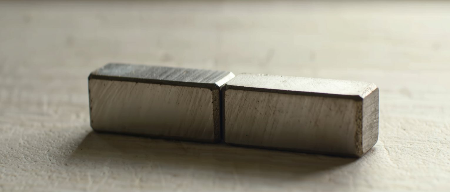 two lapped steel gauge blocks, their faces smooth and unstamped, wrung together into one body, the joint invisible