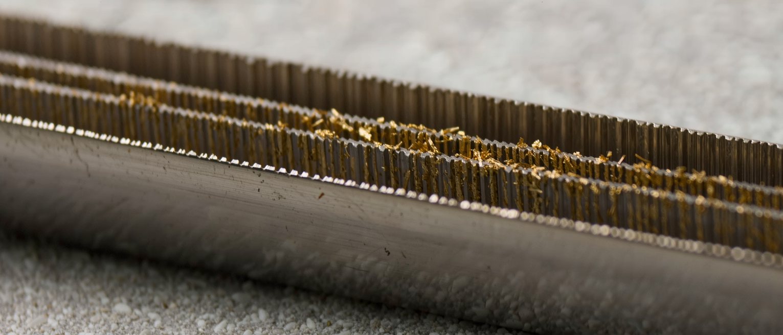 the cut teeth of a steel file with brass swarf caught between the rows