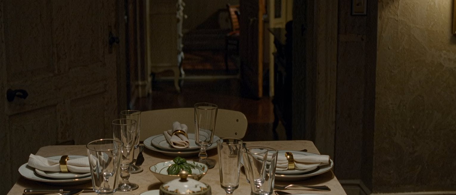 a holiday table laid before anyone has sat down, every place set identically and one extra chair added at the end
