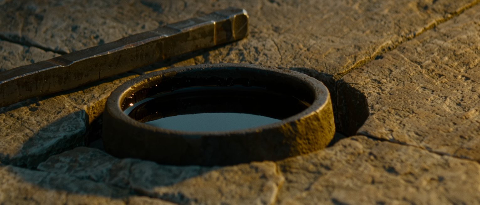 a blacksmith's quench tub of still water with a finished iron bar on the stone beside it