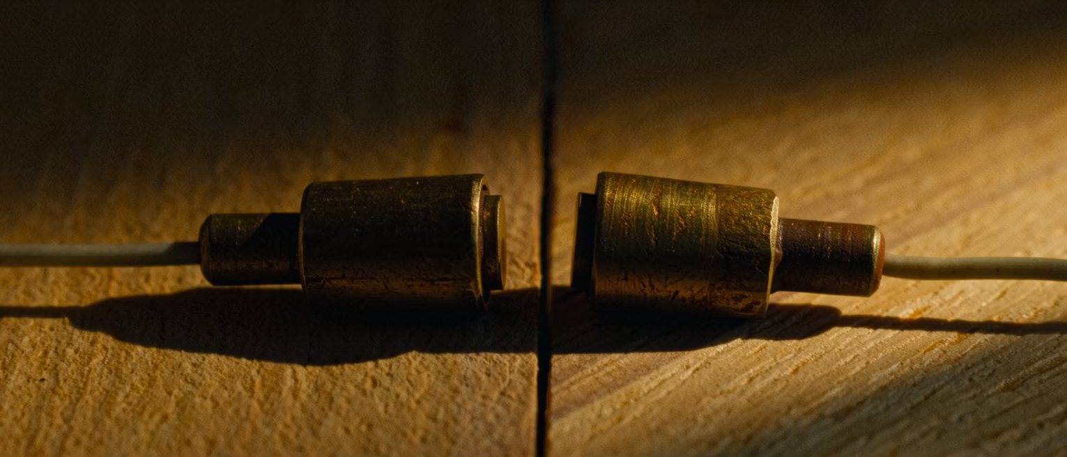 two brass terminals set apart on a board with one wire run between them