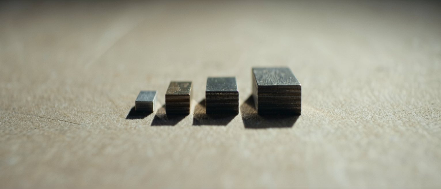 a set of gauge blocks laid out in a row, each one a different thickness