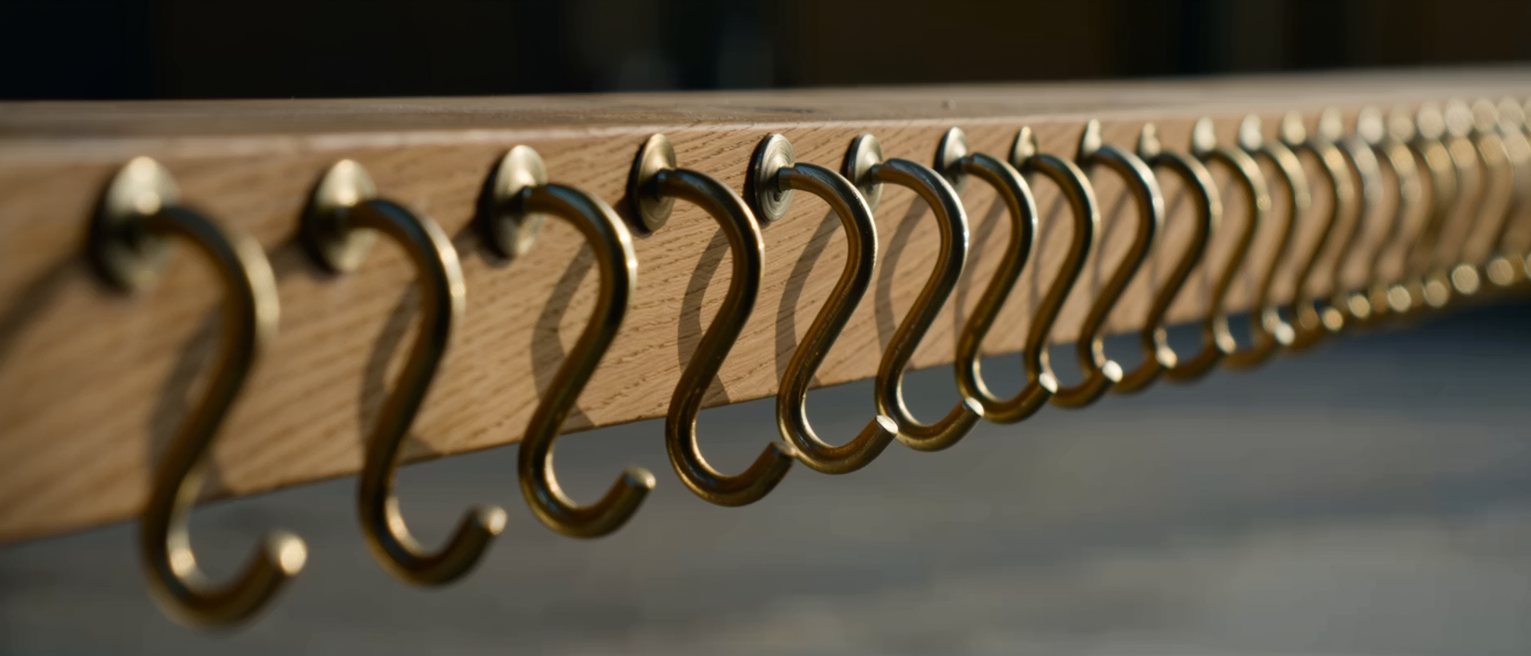 a run of identical brass hooks screwed along an oak rail