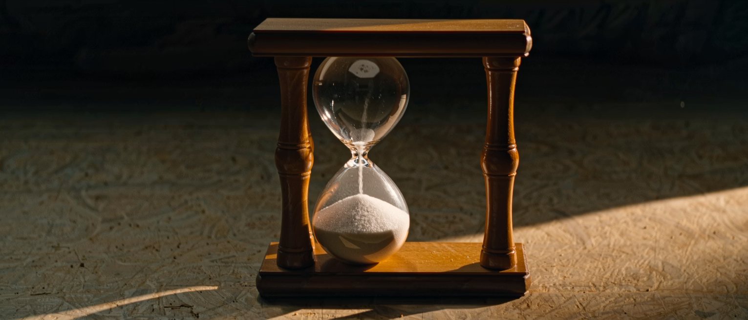 a sand glass in a turned wooden frame, the sand part run through