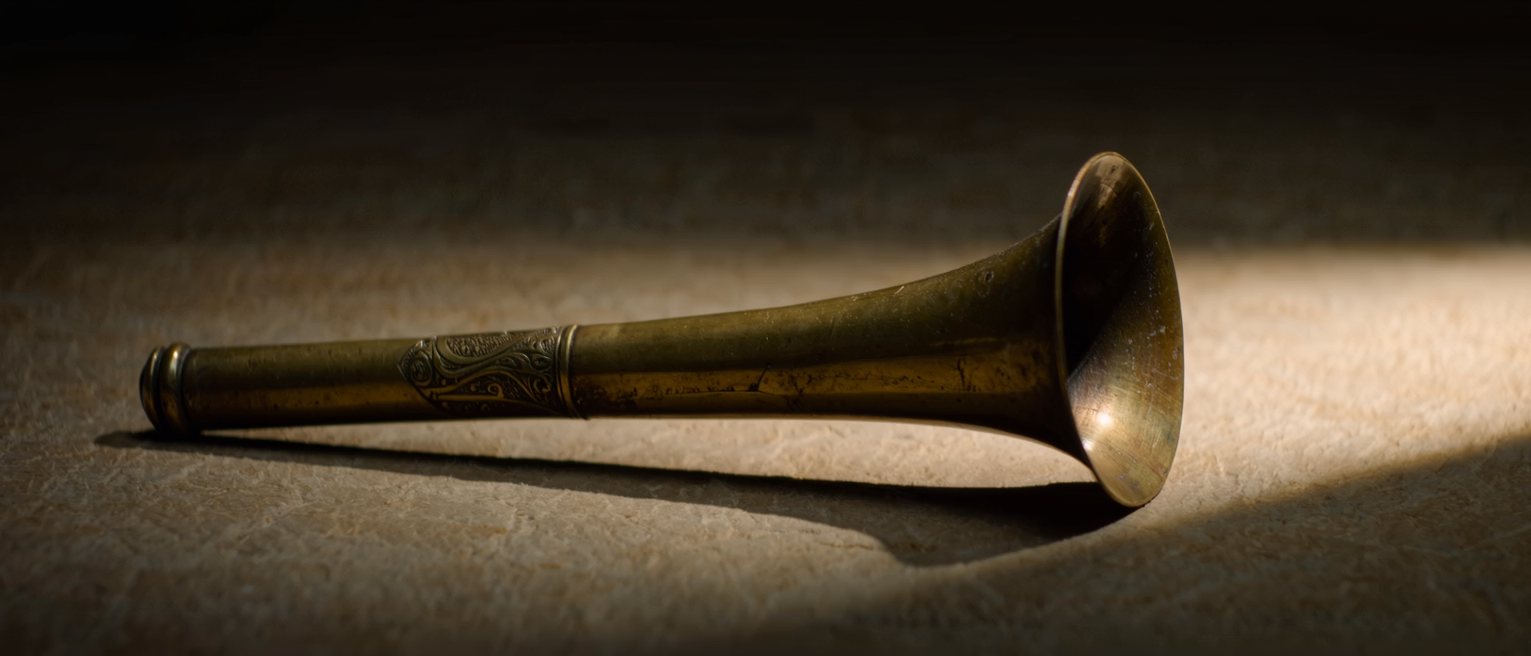 a long brass horn of an old gramophone, its mouth open and dark inside