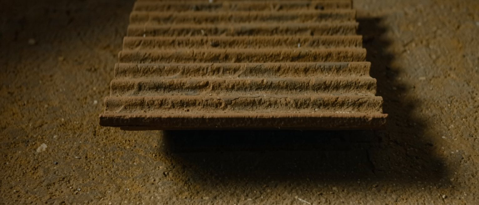 a hand-made clay roof tile, its underside carrying the ridges left by the mould