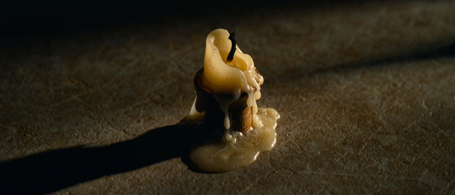 a candle burned down to a stub in its holder, the wax run over the edge