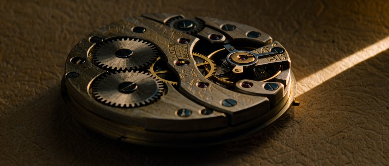 the open back of a clockwork movement, its jewels and springs exposed and still