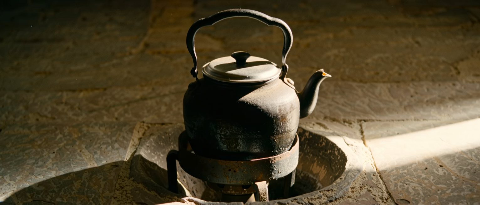 a cast-iron kettle standing off the heat on a stone hearth, its lid closed